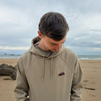Khaki Overcut hooded sweatshirt with Jeep Wrangler embroidery, worn on a beach